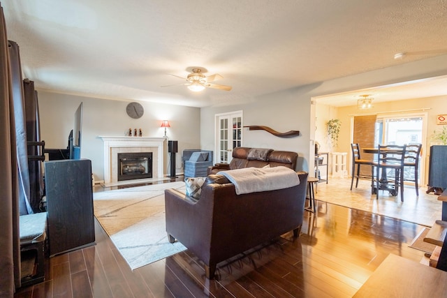 living room with a tiled fireplace, hardwood / wood-style flooring, and ceiling fan