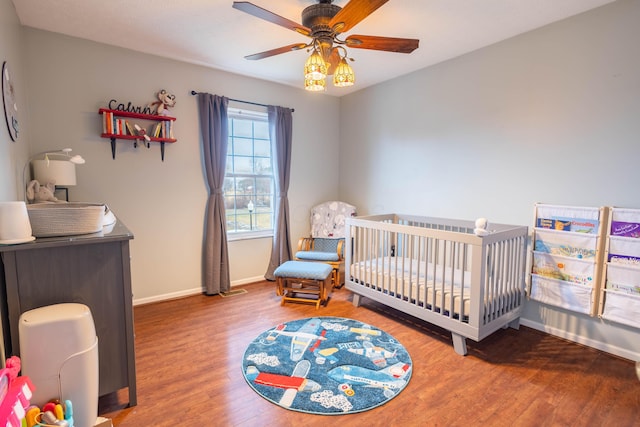 bedroom featuring hardwood / wood-style flooring, ceiling fan, and a crib