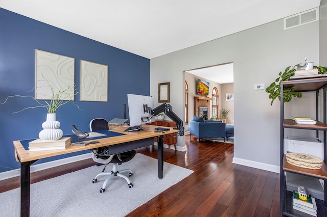 home office featuring wood-type flooring, visible vents, and baseboards