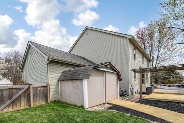 rear view of house featuring fence, a storage shed, a yard, a wooden deck, and an outdoor structure