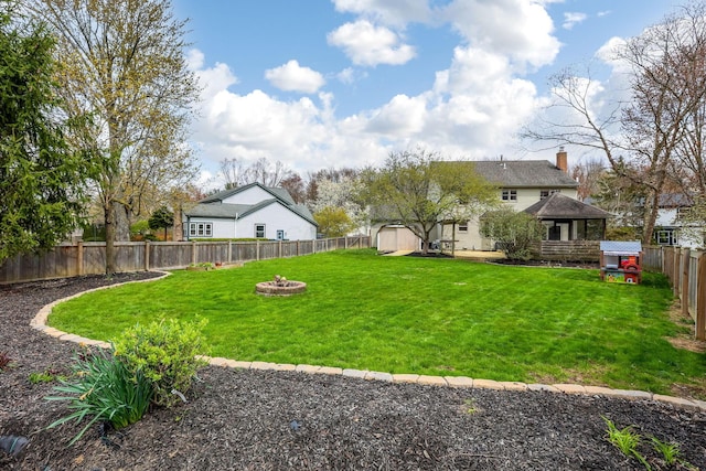 view of yard with a fire pit, an outbuilding, a shed, and a fenced backyard