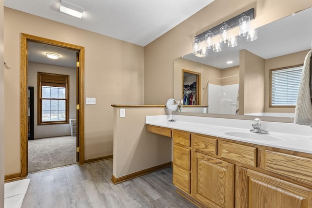 bathroom with hardwood / wood-style flooring, vanity, and a shower