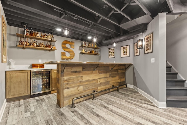 bar with light hardwood / wood-style flooring, wine cooler, and decorative light fixtures