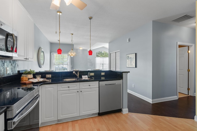 kitchen with appliances with stainless steel finishes, white cabinets, a sink, and visible vents