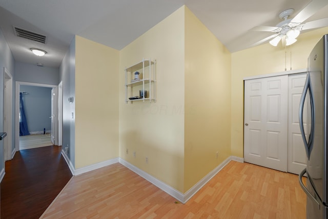 hall with light wood-type flooring, baseboards, and visible vents