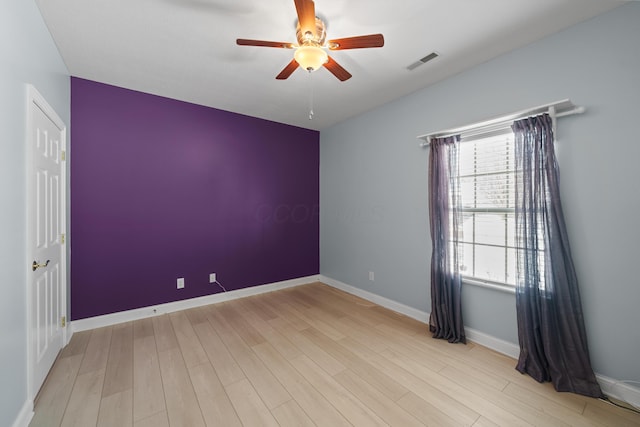 unfurnished room with light wood-type flooring, baseboards, visible vents, and ceiling fan