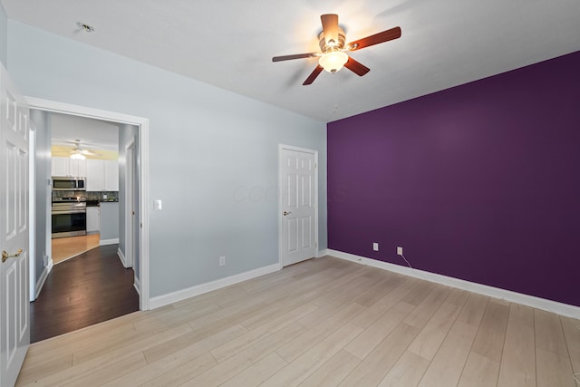 unfurnished room featuring a ceiling fan, light wood-style flooring, and baseboards