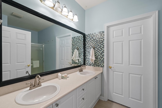 full bathroom with a sink, a shower stall, and double vanity