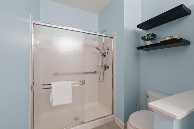 bathroom featuring a shower stall, toilet, and baseboards