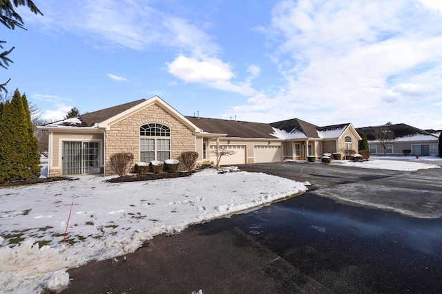 view of front facade featuring stone siding, driveway, and an attached garage