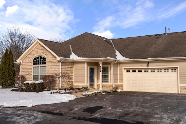 ranch-style home featuring stone siding, aphalt driveway, an attached garage, and a shingled roof