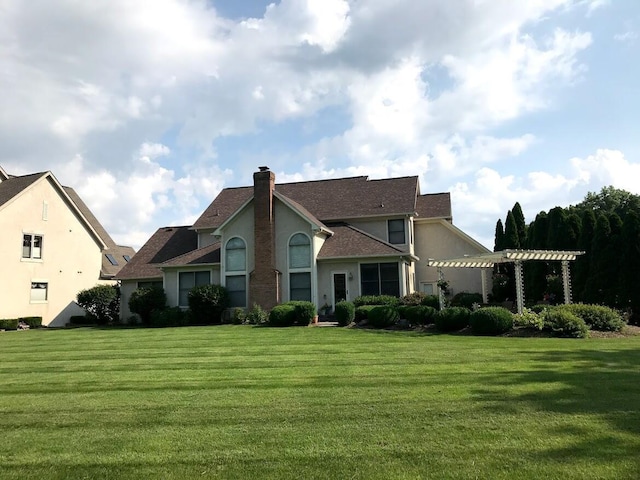 back of property with stucco siding, a lawn, a pergola, and a chimney