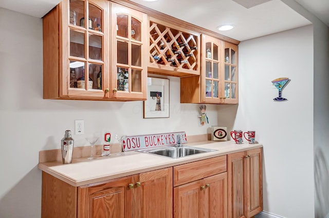 kitchen with light countertops, glass insert cabinets, and a sink