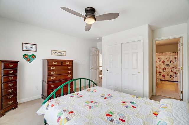 bedroom featuring a ceiling fan, a closet, connected bathroom, baseboards, and light colored carpet