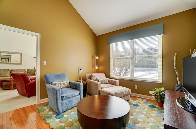 living area with visible vents, baseboards, wood finished floors, and vaulted ceiling