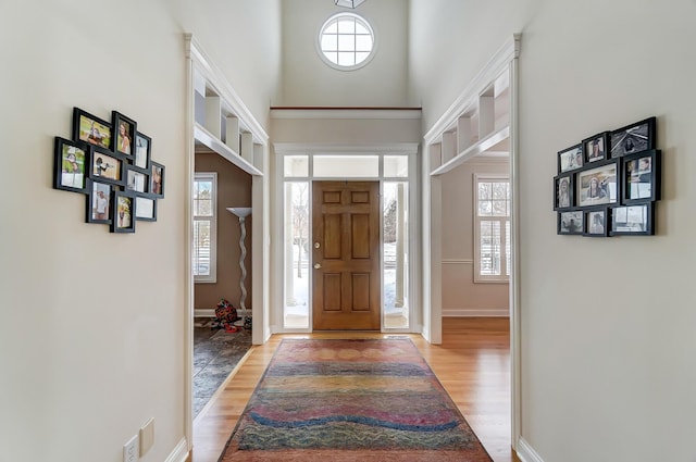 entrance foyer with a towering ceiling, baseboards, and light wood finished floors