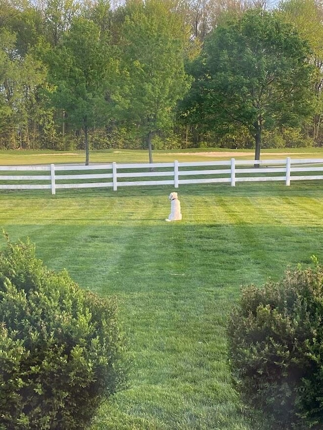 view of community featuring fence, a lawn, and a rural view