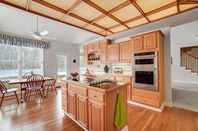 kitchen featuring a kitchen island, black electric stovetop, double oven, coffered ceiling, and a ceiling fan