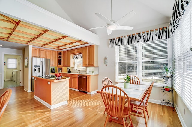 kitchen with coffered ceiling, a kitchen island, appliances with stainless steel finishes, a healthy amount of sunlight, and washing machine and clothes dryer