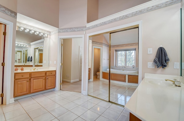 full bath featuring tile patterned floors, toilet, two vanities, and a sink