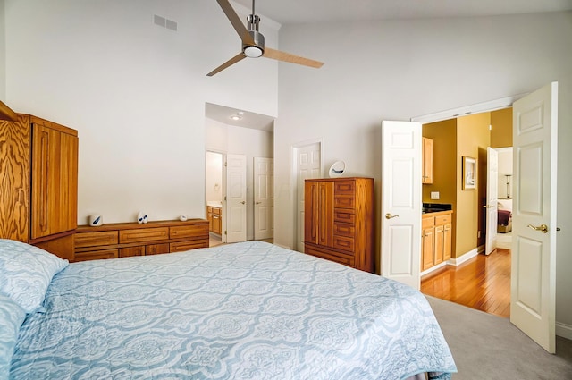 bedroom with visible vents, light carpet, high vaulted ceiling, ensuite bathroom, and ceiling fan