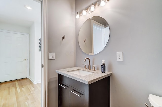 bathroom featuring baseboards, toilet, wood finished floors, and vanity