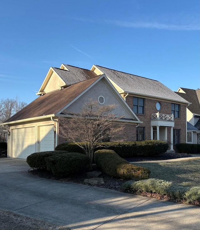 view of front of home with an attached garage, brick siding, driveway, and stucco siding