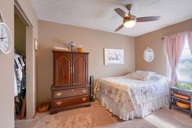 bedroom with a closet, light carpet, a ceiling fan, and a textured ceiling