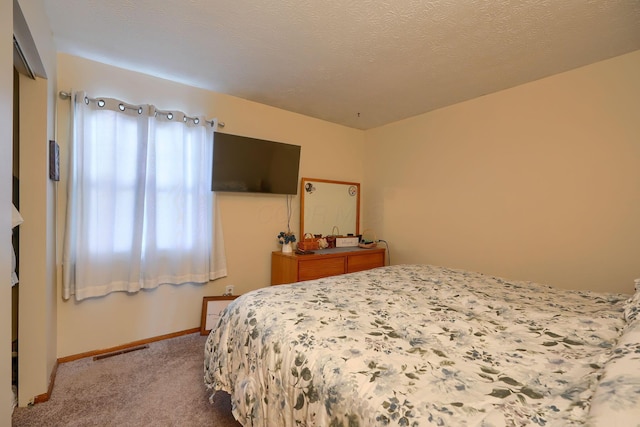 bedroom featuring carpet flooring, baseboards, visible vents, and a textured ceiling