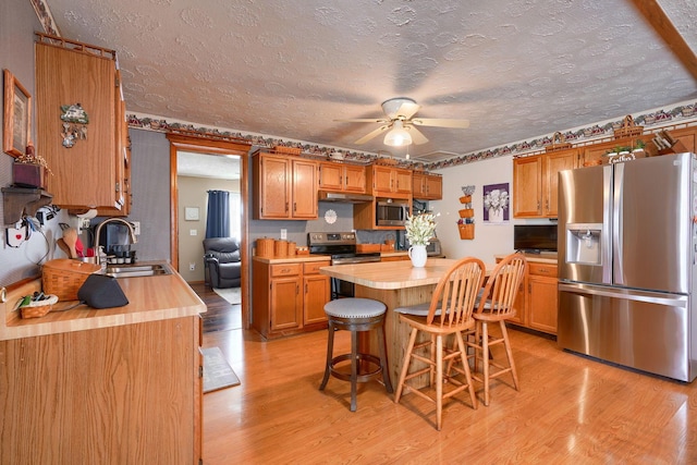 kitchen featuring a kitchen island, a kitchen bar, butcher block countertops, and stainless steel appliances