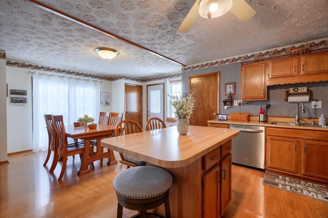 kitchen with a center island, a sink, light wood-style floors, dishwasher, and brown cabinetry