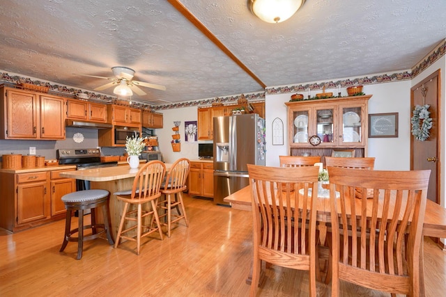 dining room with a textured ceiling, a ceiling fan, and light wood-type flooring