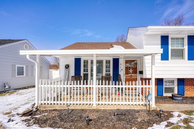 split level home featuring roof with shingles and a porch