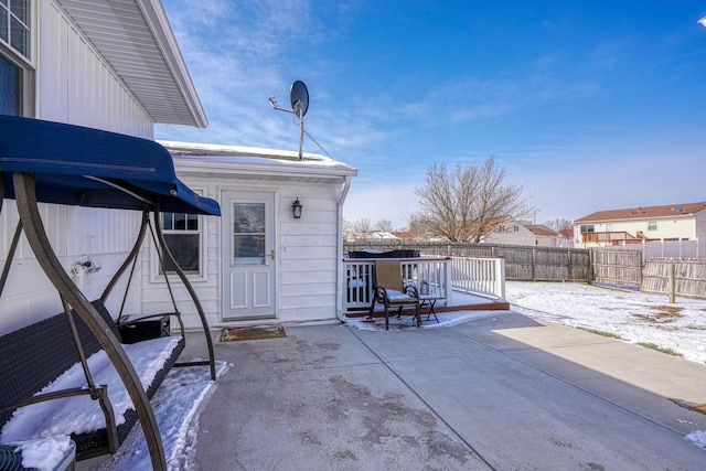 snow covered patio with a fenced backyard