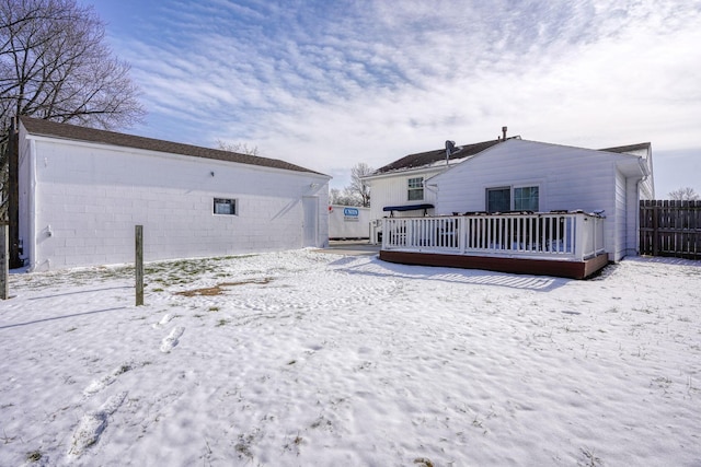 snow covered rear of property featuring a wooden deck and fence