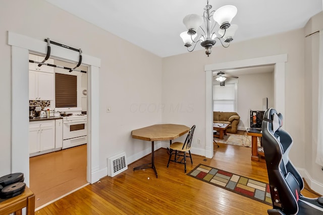 dining room with ceiling fan with notable chandelier and light wood-type flooring