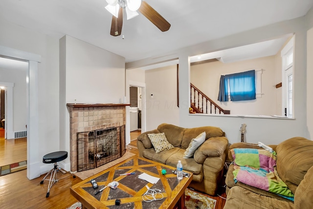 living room with a brick fireplace, hardwood / wood-style flooring, and ceiling fan