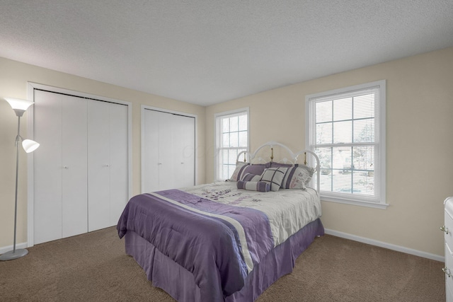 bedroom featuring multiple closets, dark carpet, and multiple windows