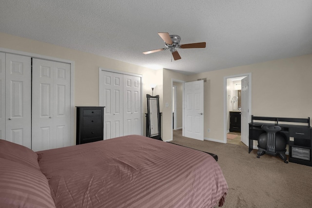 carpeted bedroom with ceiling fan, connected bathroom, a textured ceiling, and two closets