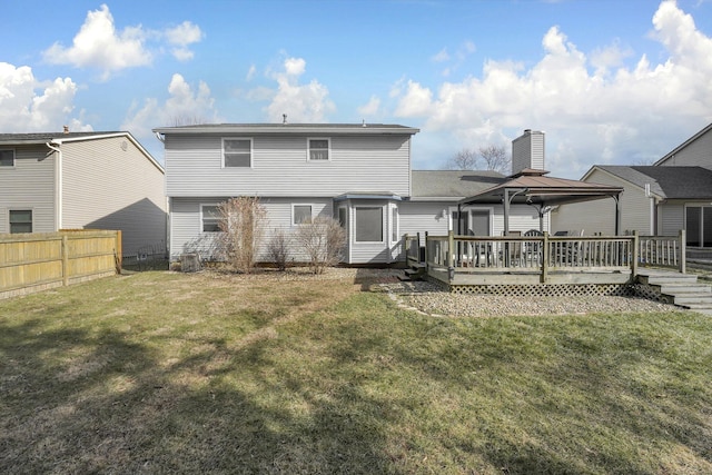 back of property featuring a gazebo, a wooden deck, and a lawn