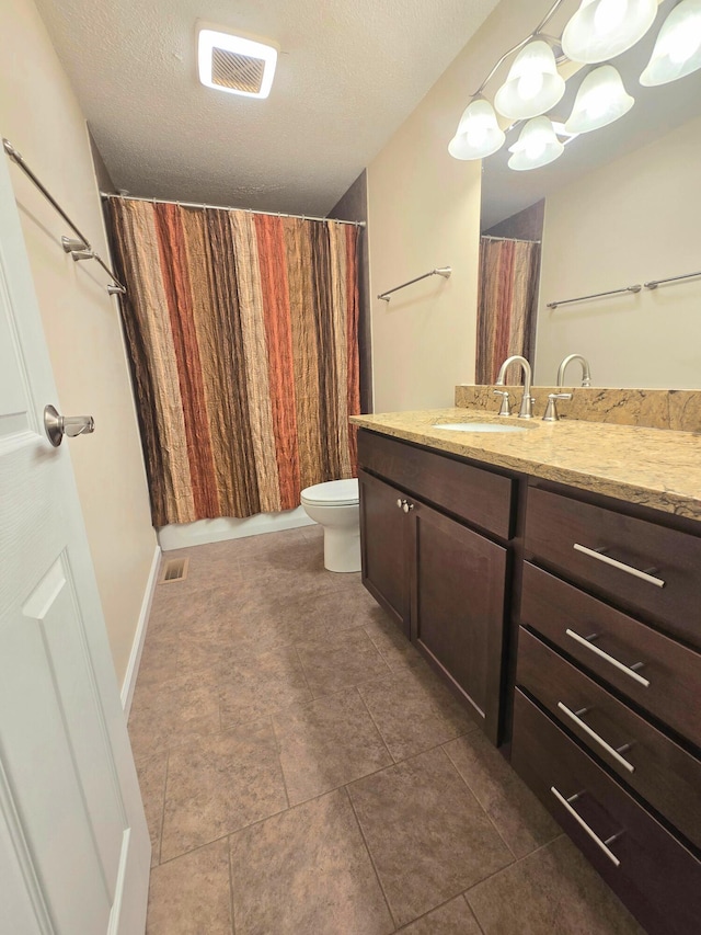 bathroom with vanity, toilet, tile patterned flooring, and a textured ceiling