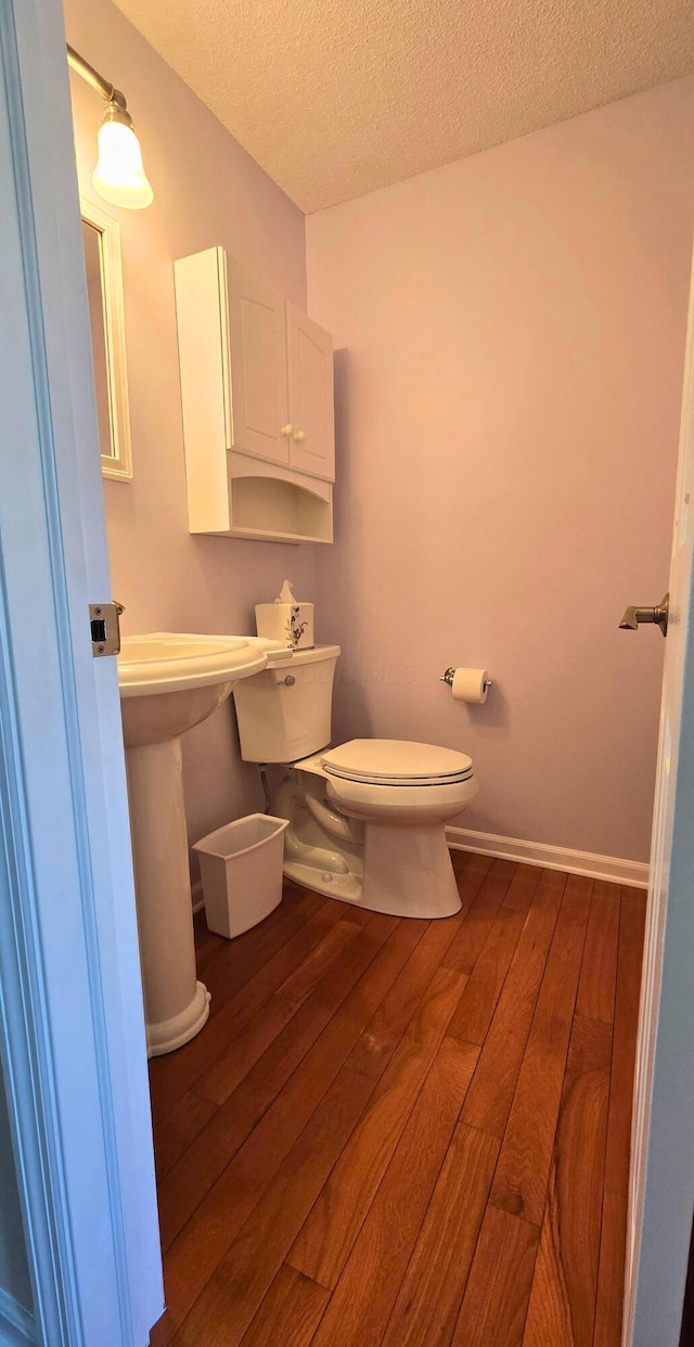 bathroom with hardwood / wood-style floors, a textured ceiling, and toilet