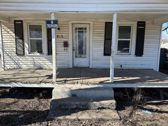 view of exterior entry featuring a wooden deck and a porch