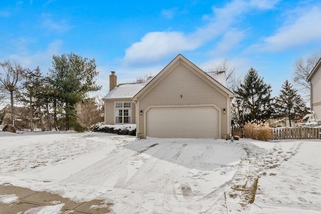 view of front of house with a chimney, an attached garage, and fence