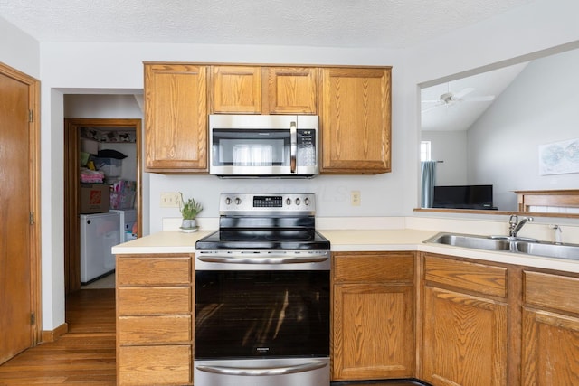 kitchen featuring stainless steel appliances, a sink, light countertops, brown cabinets, and washing machine and clothes dryer