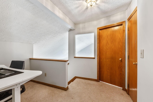 home office featuring light carpet, a textured ceiling, and baseboards