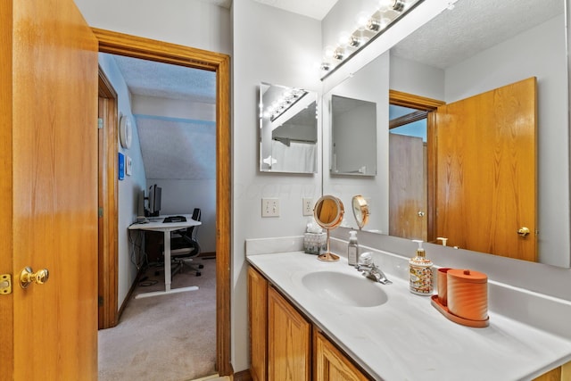 bathroom with lofted ceiling, a textured ceiling, and vanity