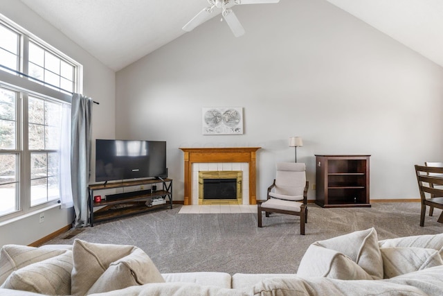 living area featuring light carpet, high vaulted ceiling, a tiled fireplace, and a healthy amount of sunlight