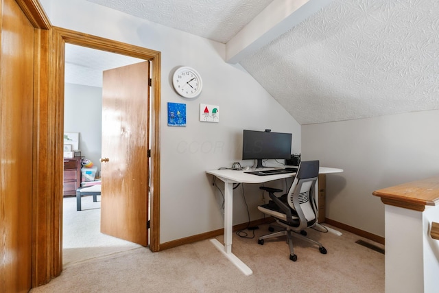 office space featuring baseboards, vaulted ceiling, a textured ceiling, and light colored carpet