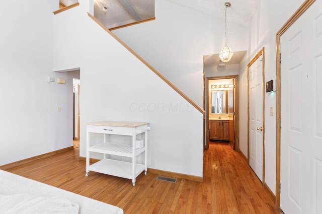 entrance foyer featuring high vaulted ceiling, baseboards, visible vents, and wood finished floors